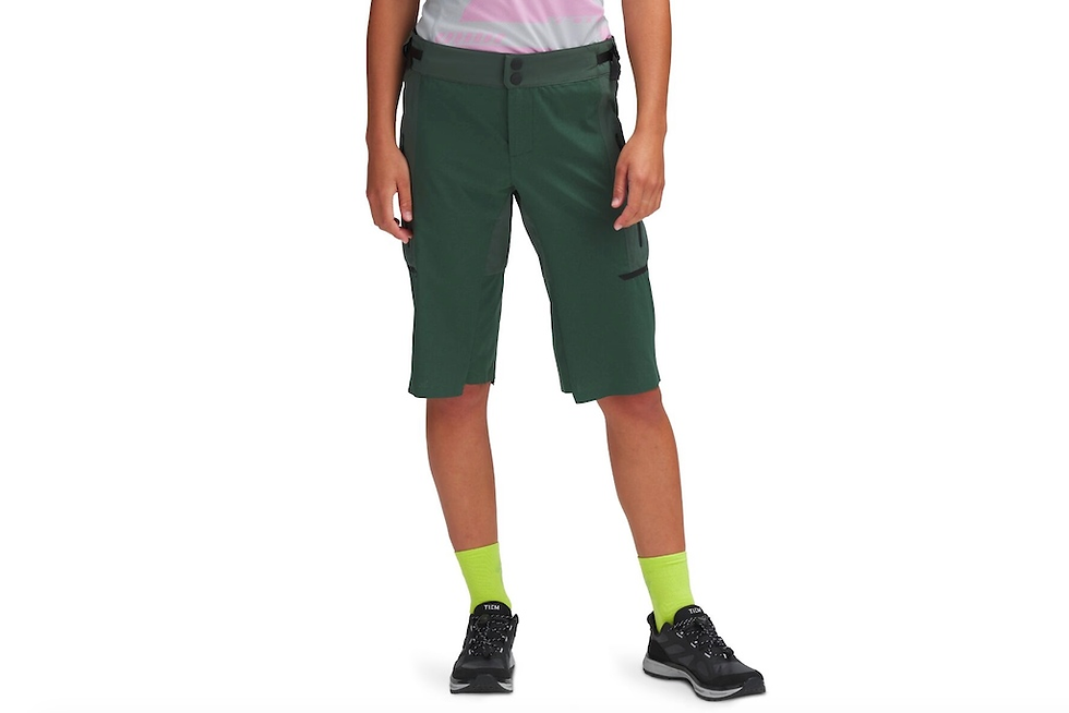 Person wearing green knee-length shorts and bright green socks with black sneakers. Background is plain white. Casual and sporty vibe.