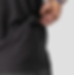 Hand placing sunglasses in a dark gray shirt pocket against a light background. The shirt and pants are both gray, with a casual mood.