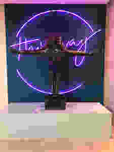 Neon sign reads 'this way' with a statue of a diver in front of it