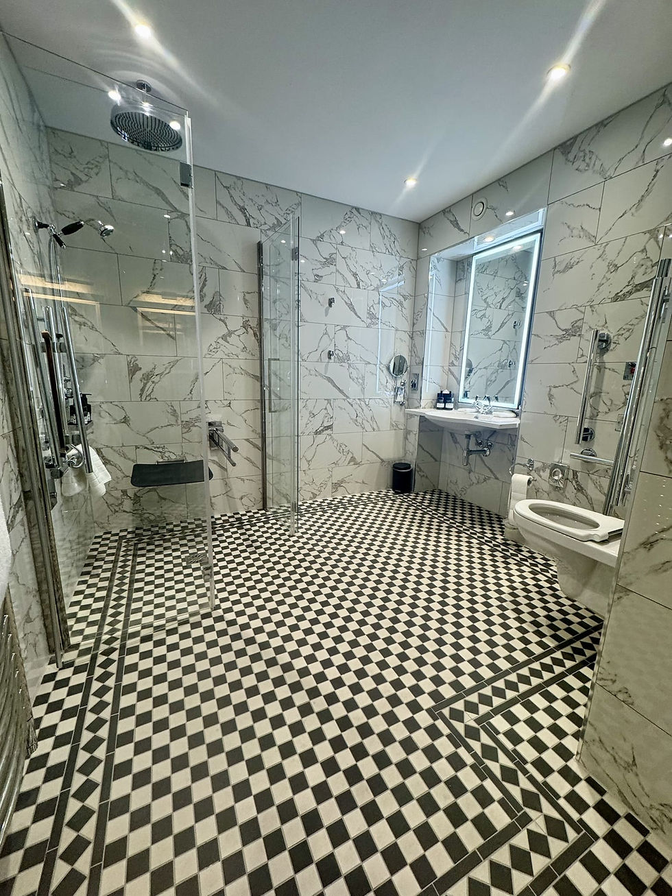 Modern marble bathroom with walk-in shower, glass doors, vanity mirror, and black-and-white checkered floor, bright and clean