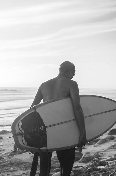Black and white of a surfer walking with his surfboard
