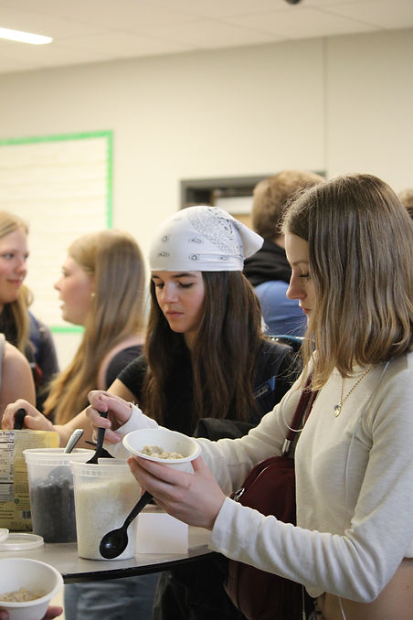 Allie Ward (10) and Ingrid Stockman (10) serve up dishes of oatmeal at the healthy eating station on Monday. This station was the first event of a week focusing on social, mental, and physical health. Photo Credit: Vanessa Ibarra (11)