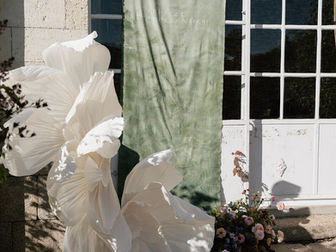 Fleurs géantes en papier installées devant le Château de la Brulaire à Beaupréau pour une scénographie florale de mariage. Décoration de cérémonie, installation florale sur mesure et création immersive réalisées par Loumer, studio floral durable spécialisé dans les mariages haut de gamme, les fleurs en papier, les fleurs géantes, les décors de cérémonie, les arches florales, la location de décors floraux, l'installation de mariage, à Nantes, en Loire-Atlantique, dans le Maine-et-Loire et partout en France.