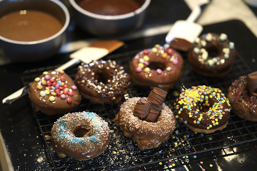 Mit Schokoladenglasur glasierte und bunt dekorierte Donuts trocknen auf einem Kuchengitter aus