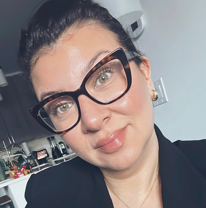 Woman wearing glasses, looking towards the camera, with a black blazer about Boho Chic Beauty.