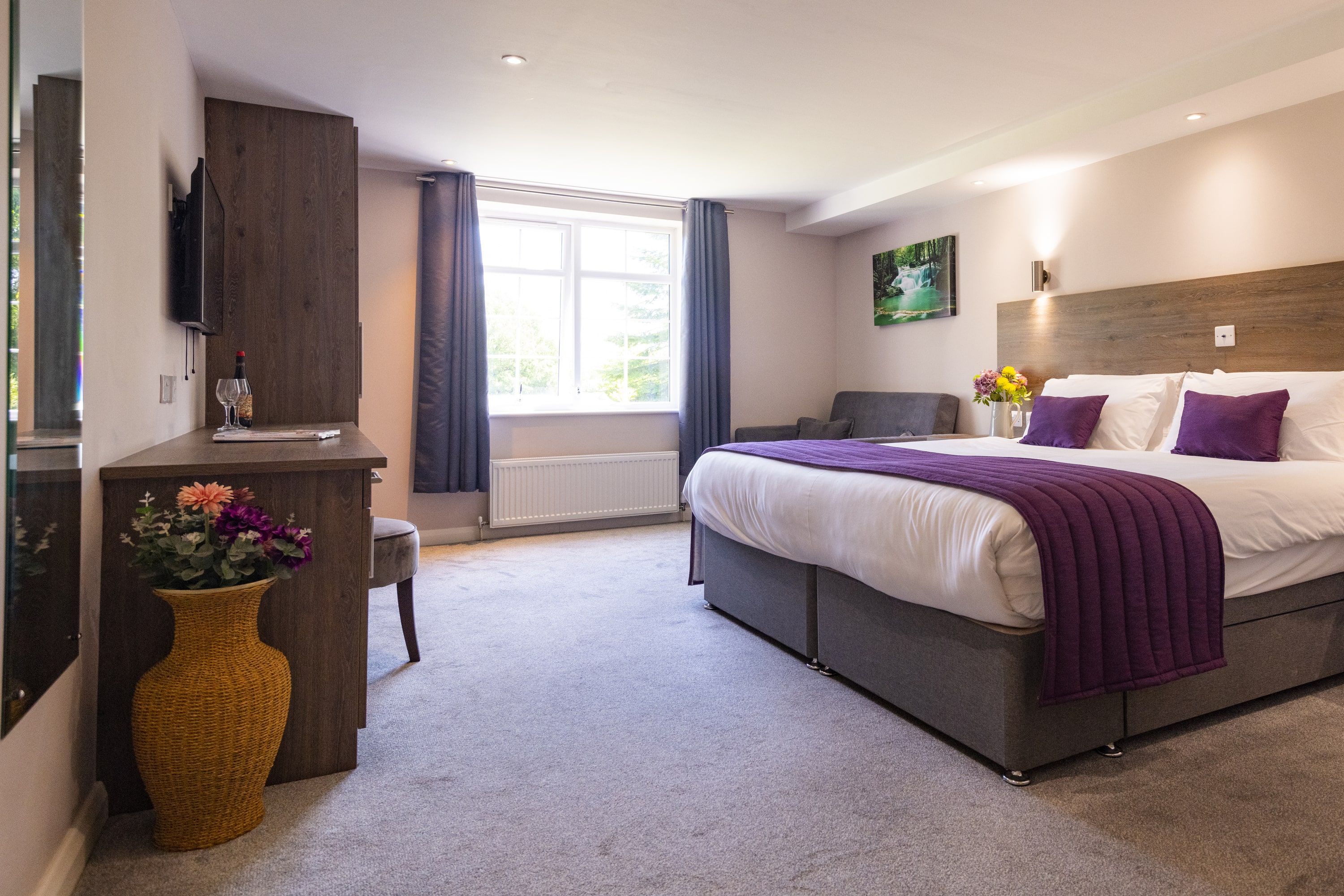 Spacious hotel room with large bed, desk, and window