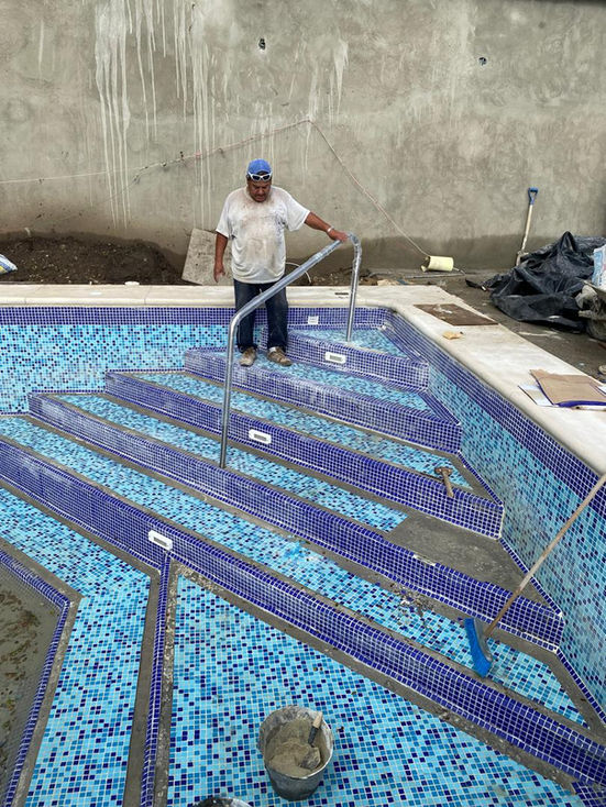 Worker installing tiles in a swimming pool.