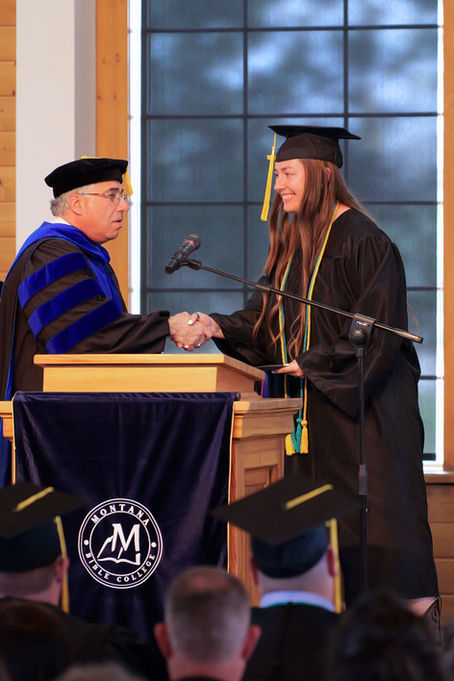 Montana Bible College 2026 graduate Noel Chittenden shakes hands with MBC Vice President of Academic Affairs Dr. Andre Gazal during the 2026 graduation ceremony.