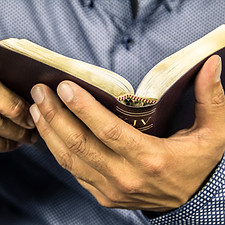 A bible is open and in hand.