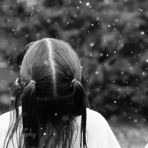 A girl sits on a concrete block with a lanyard around her waist that says boston