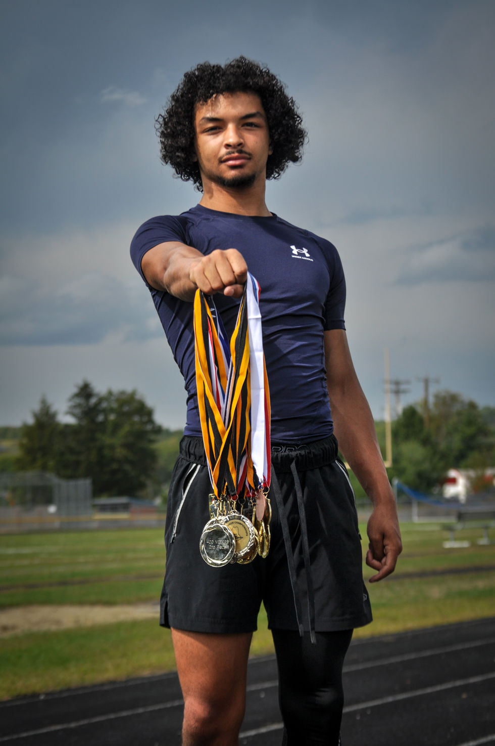 A man holds up a bunch of medals including one that says silver