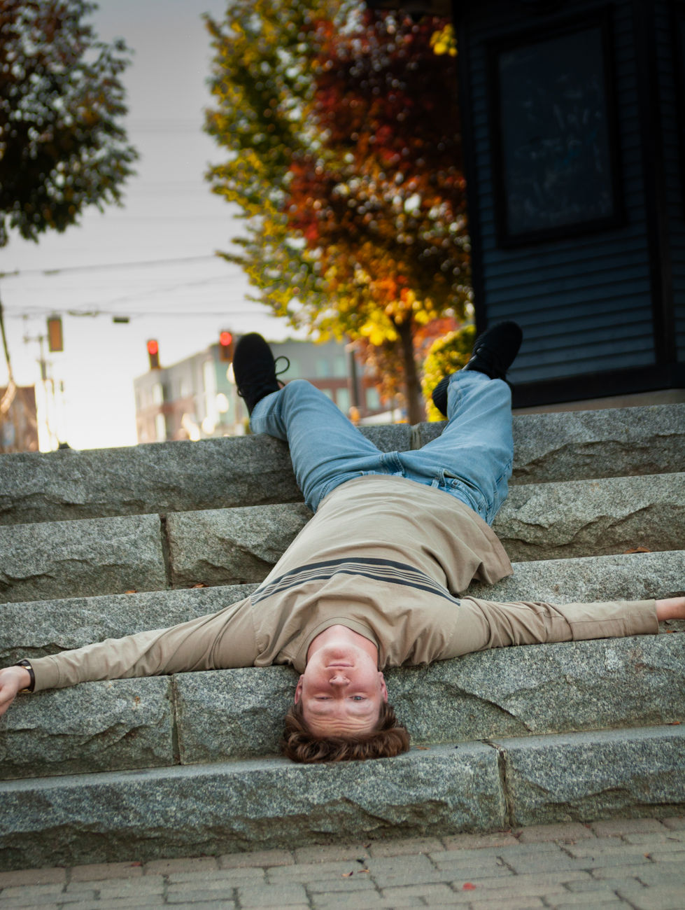A girl sits on a concrete block with a lanyard around her waist that says boston