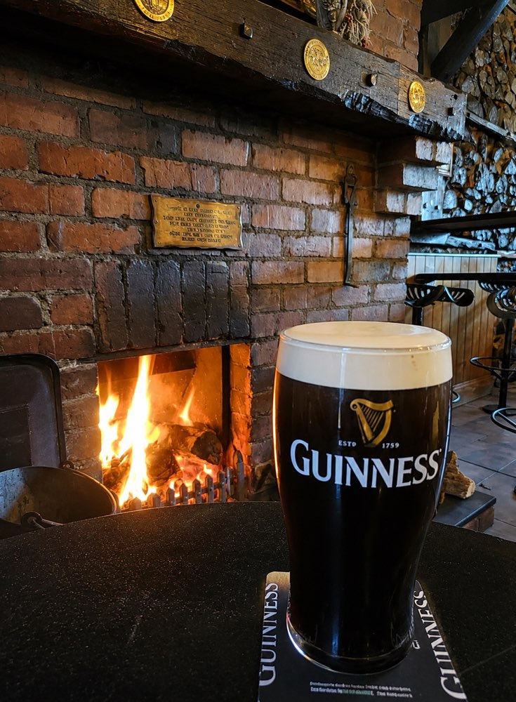 Pint of Guinness sitting on pub table in front of roaring fire