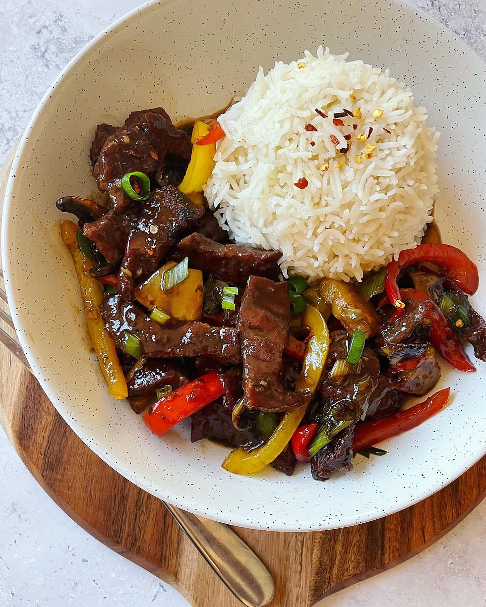 In bowl honey chilli beef with boiled rice.