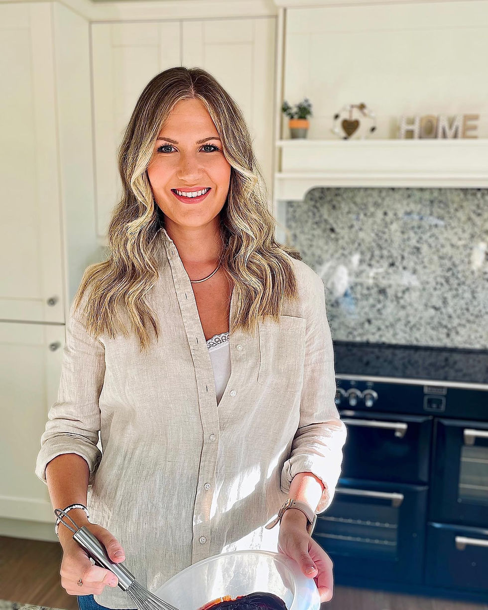 Jill Stewart standing in kitchen with whisk in hand smiling