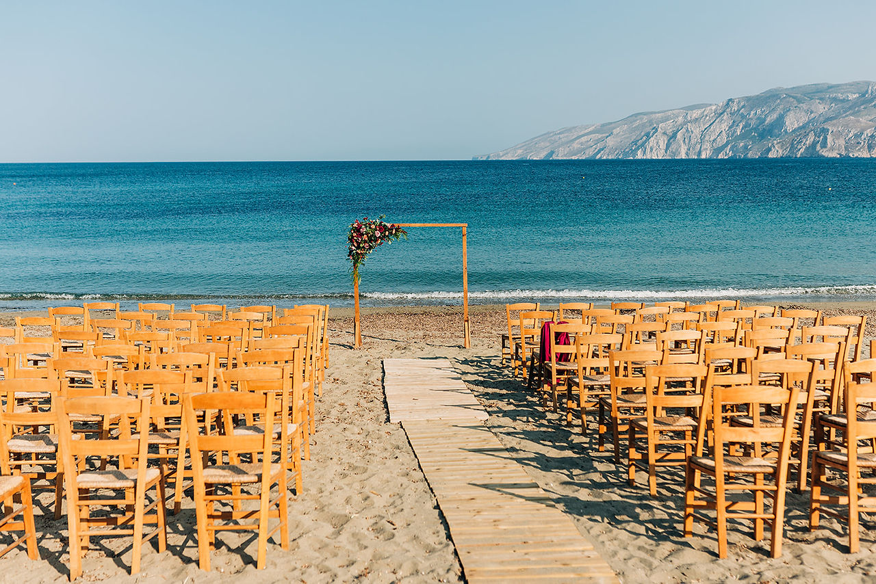 wooden chairs on beach for wedding ceremony and arch