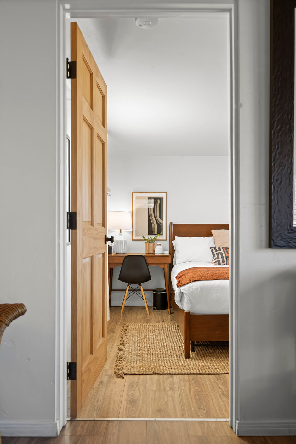Cozy modern bedroom with wooden door, neutral decor and natural light, real estate interior photo in Los Angeles.
