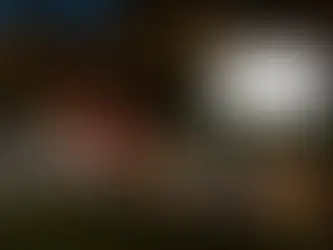 A cozy outdoor movie night in a backyard at night, with families sitting on blankets, bean bags, and lawn chairs, watching a movie on a large inflatable screen. String lights hang overhead, a projector shines from a small table, and lanterns and snack tables create a warm, inviting atmosphere.