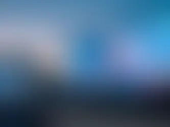 A large outdoor concert stage featuring a massive LED video wall displaying a colorful city skyline at dusk, with an audience seated in front of the stage and lighting truss structures surrounding the screen.