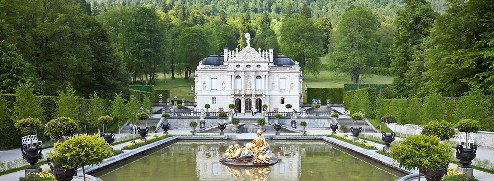 A picture of a palace and garden in a forested area.