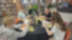 Four students in the library, reading books at a table.