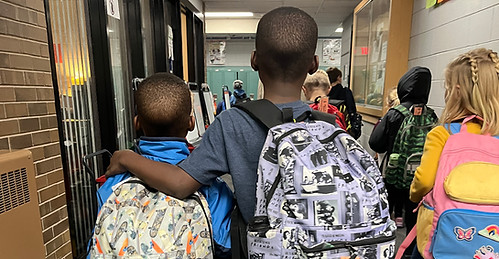 Photo of students walking through a hallway in a school building.