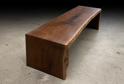 Live edge bench shown with two wooden waterfall legs made with a live edge walnut slab, natural tree slice.