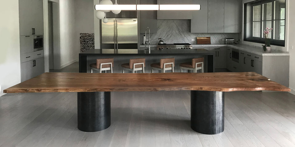 Live edge dining table shown with column base on a live edge walnut wood slab.