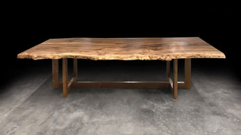 Live edge dining table shown with wood trestle base with a live edge maple wood tree slice slab.