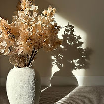 sunlit faux flowers in textured vase used to stage modern or more traditional homes