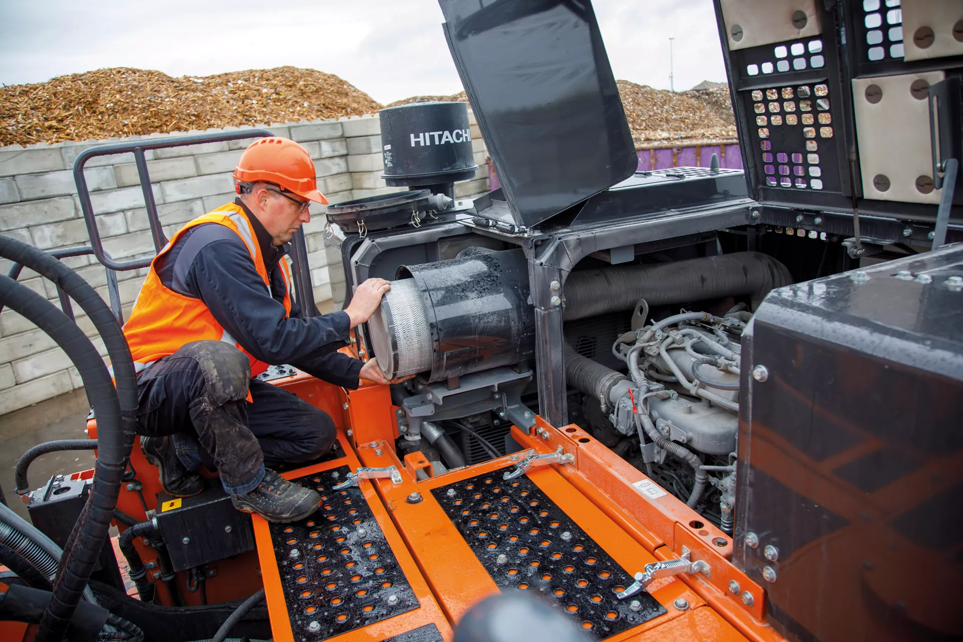 Technician servicing the engine of a Hitachi excavator on-site