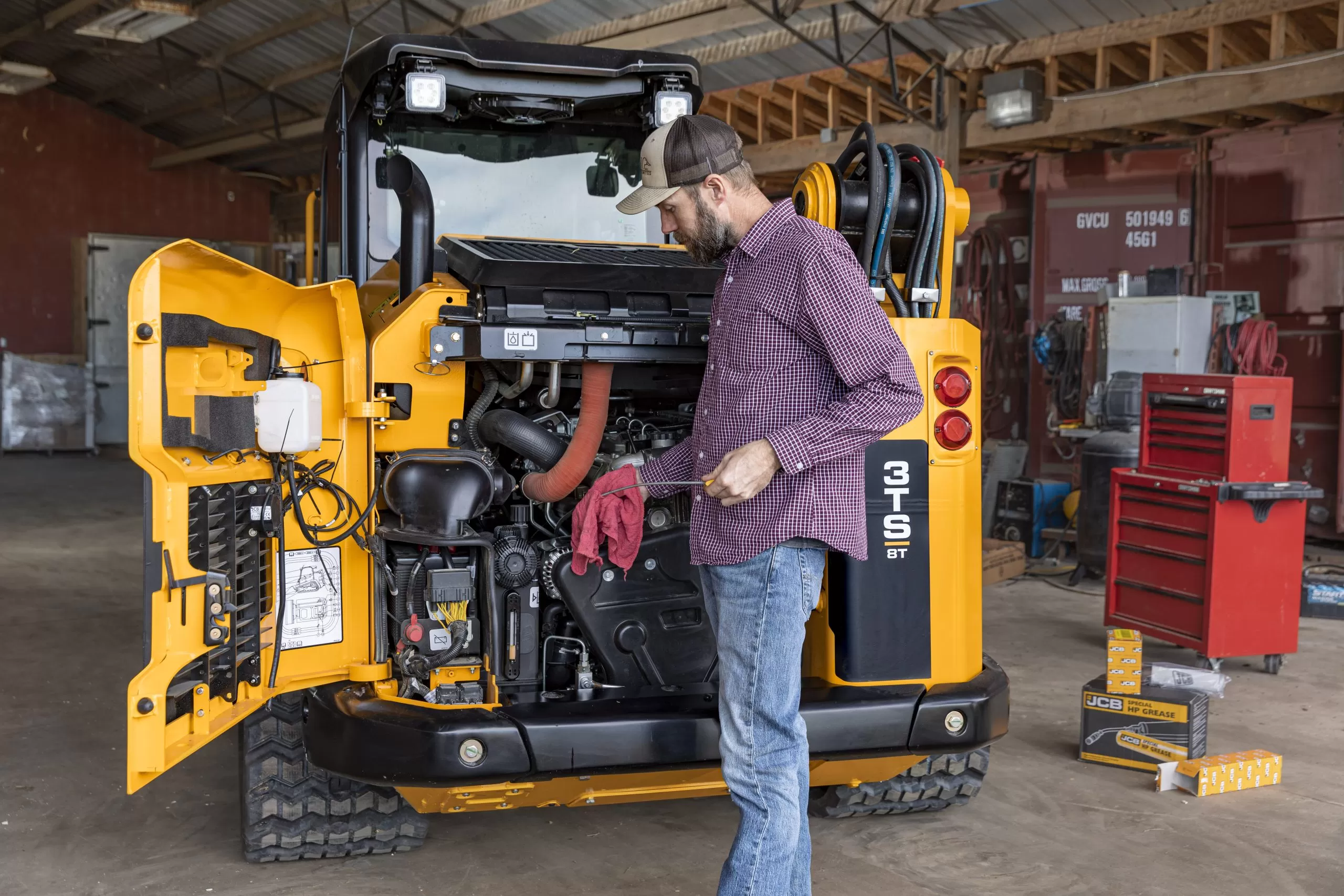JCB backhoe engine being serviced by a diesel mechanic in the shop