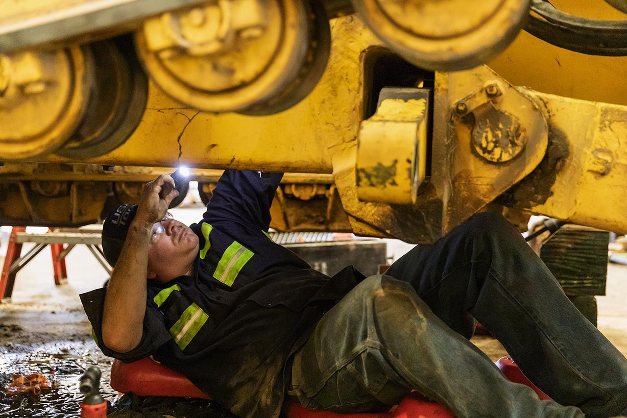Mechanic inspecting the boom of a Komatsu excavator during on-site repair