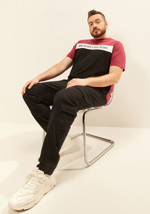 Hadi wearing a red and black tshirt and black pants, sitting on a chair