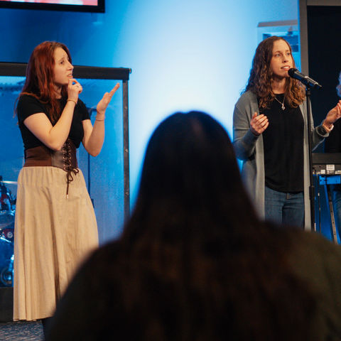 A women signing and a women worshiping