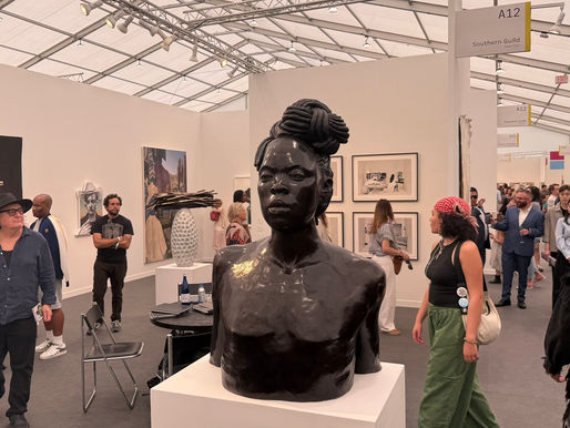 A black bust sculpture is displayed in a crowded art gallery. People are observing artworks on walls. Signs read "A12" and "Southern Guild." This sculpture, titled Amandla (Power) by artist Zanele Muholi, was presented by the Southern Guild gallery at Frieze Los Angeles 2026.