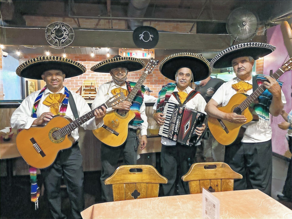 Mariachi trio in traditional charro suits performing at a Los Angeles venue.