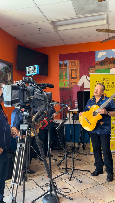 Trio Los Angeles being recorded by a camera crew during a live performance.