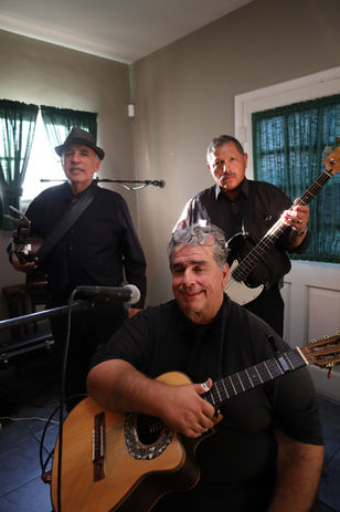 Trio musicians performing indoors with acoustic guitars and bass during an intimate private event.