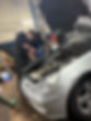 Mechanic and apprentice during repair of silver car under bonnet