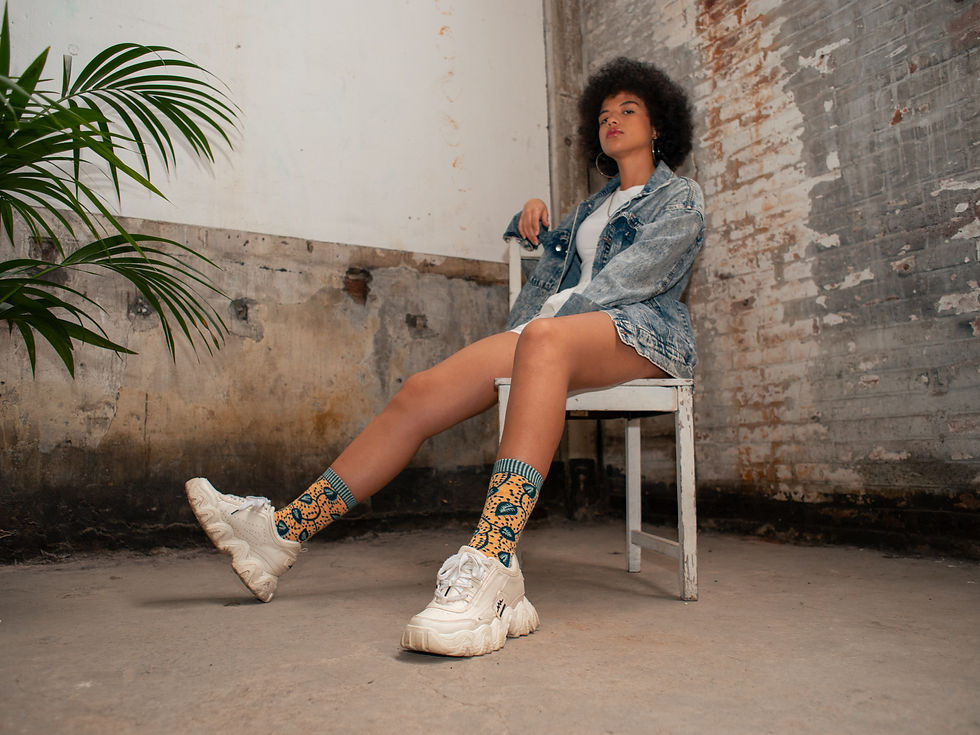 Thumbnail: A woman sitting on a chair with her Faly saffron socks and white sneakers