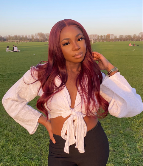 Dark skinned girl in a dark red middle part wig with loose waves