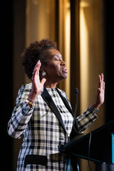 Winsome Earle-Sears standing at a podium with her eyes closed and hands raised in prayer during the September 11 prayer dinner in Washington, D.C.