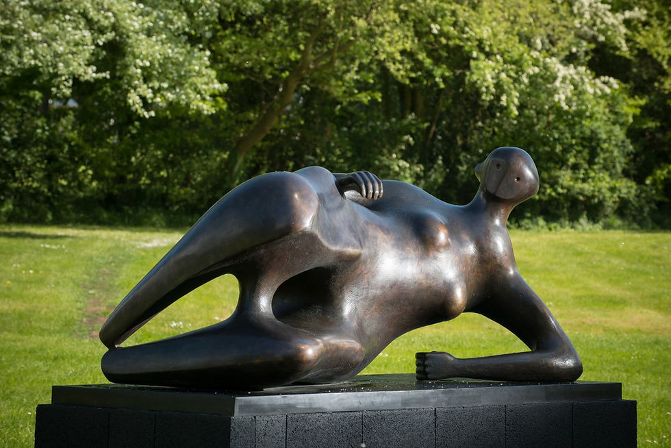 Bronze Henry Moore abstract sculpture of a reclining figure on a pedestal, set in a park with lush green trees and grass, conveys serenity.