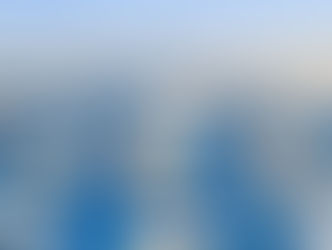 A snowy cityscape of Oulu in Finland with winter trees, buildings, and a notable clock tower in daylight. Bright blue sky and a serene, cold atmosphere.