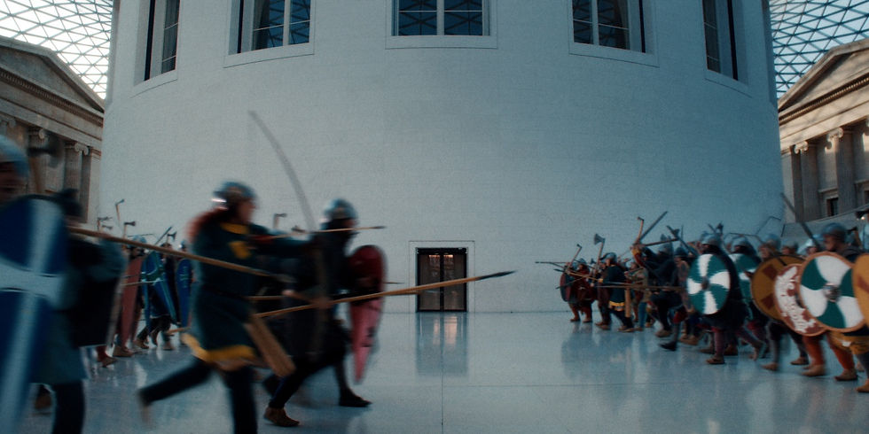 Blurred medieval fighters with spears and shields march in a bright museum hall around a white cylindrical tower.