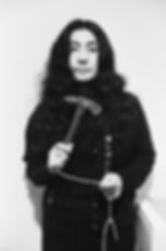 Black and white photograph of Yoko Ono looking at the camera holding a hammer