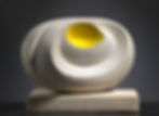 Abstract Barbara Hepworth sculpture with smooth gray curves and a bright yellow hollow center sits on a rectangular base against a dark background.