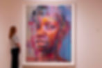 A woman in the National Portrait Gallery admires a vibrant Jenny Saville portrait with abstract splashes of color on a white wall, creating a contemplative mood.