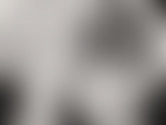 Marilyn Monroe in a white coat sits in a wicker chair, looking up. The background is softly lit, conveying a relaxed, elegant mood. Black-and-white image.